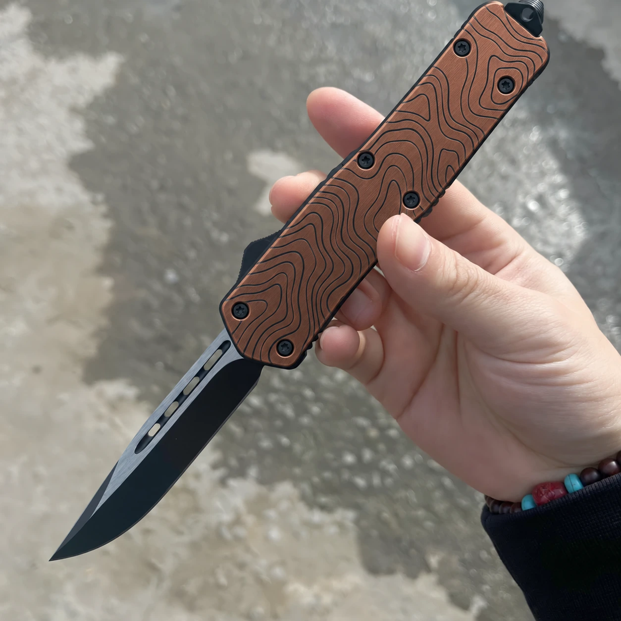 Burnt copper topographic OTF knife with black drop-point blade and five black handle fasteners